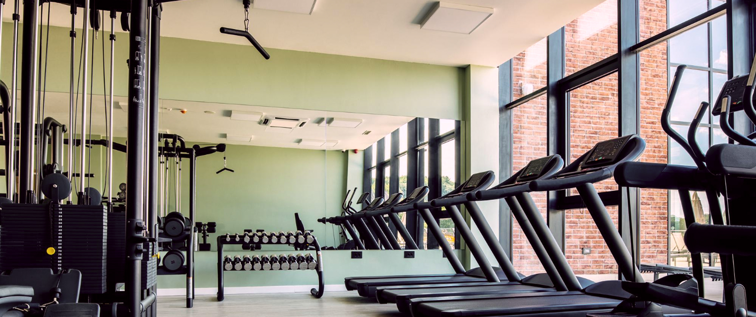 Светлый зал с окнами в пол, разными тренажерами и спортинвентарем